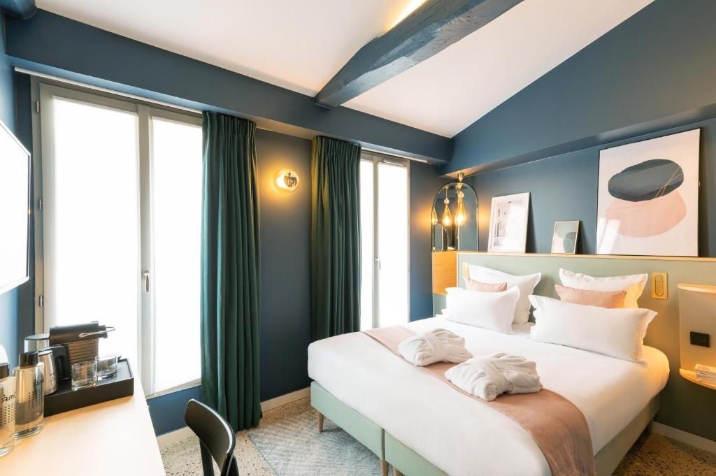 a bedroom with a large white bed with blue walls at Hôtel Amoi Paris in Paris