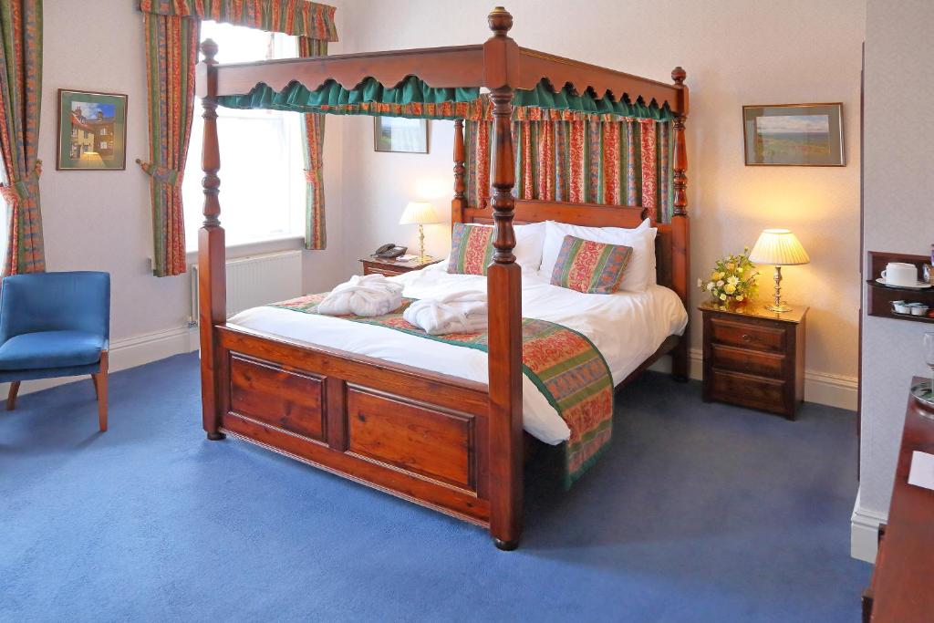 a bedroom with a canopy bed and a blue chair at Saxonville Hotel in Whitby