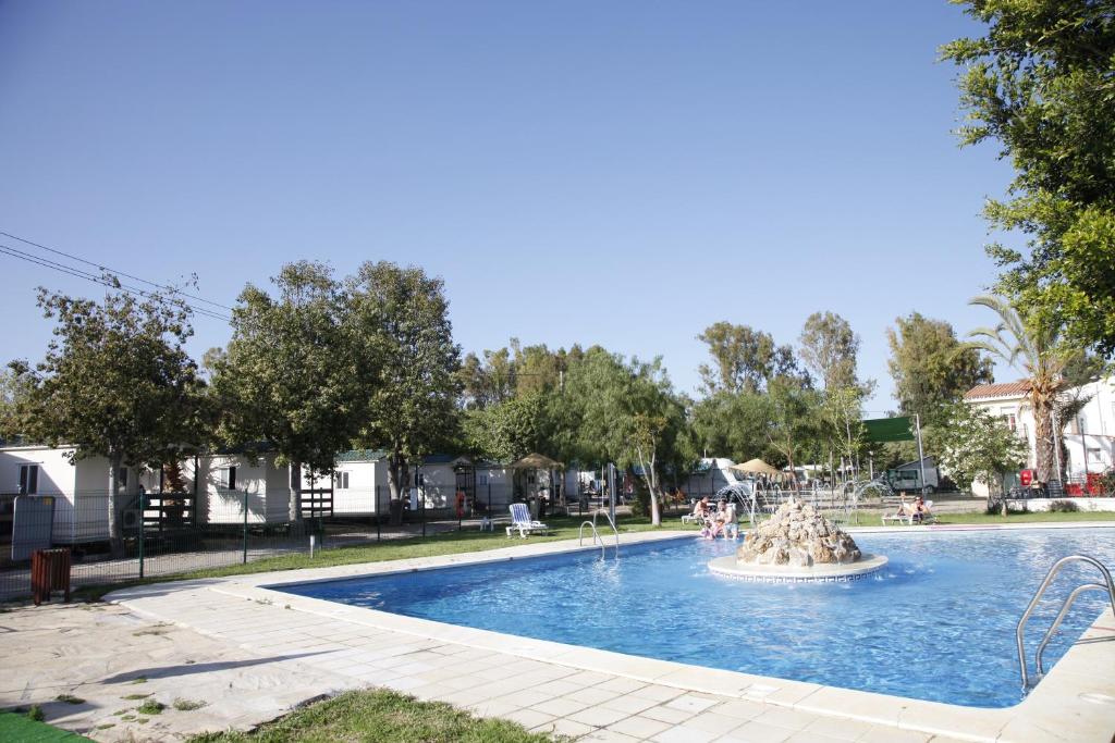 a swimming pool with a fountain in a park at Camping Valle Niza Playa in Benajarafe