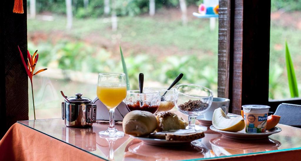 uma mesa coberta com copos de sumo de laranja e comida em Pousada Valle dos Pássaros em Penedo