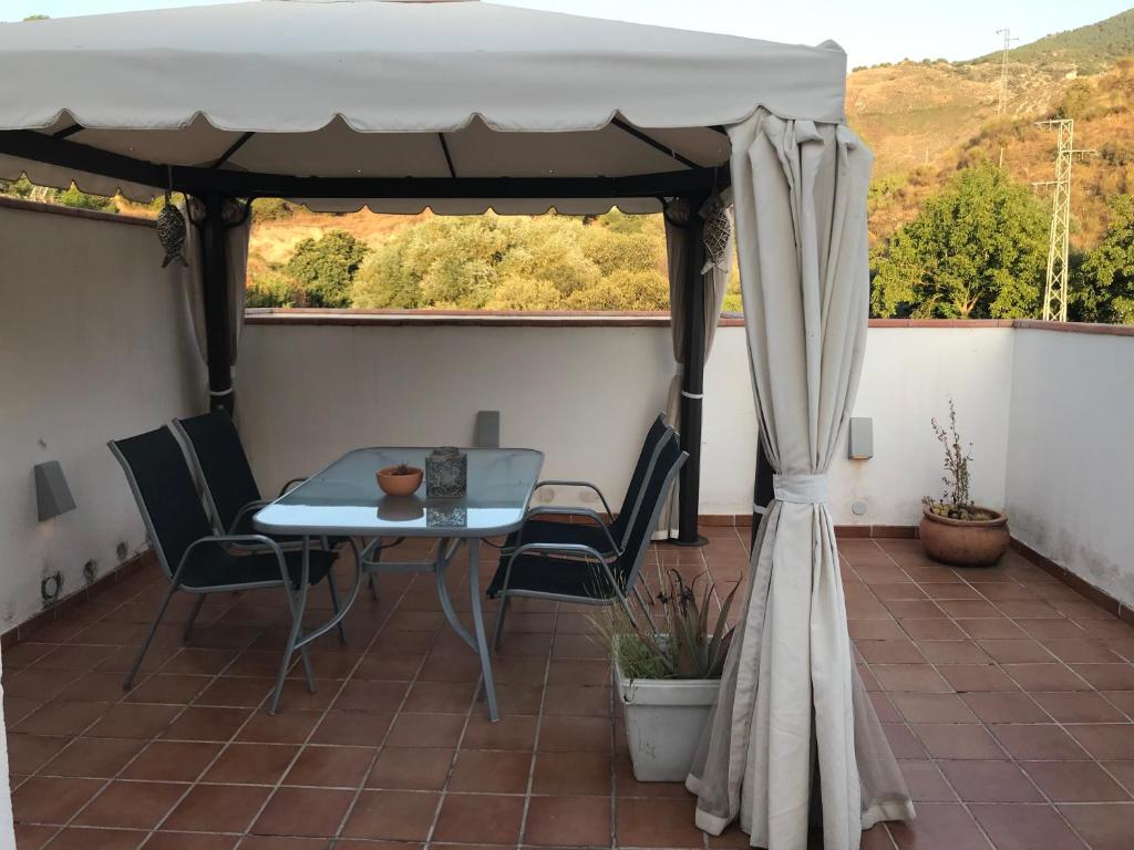 patio con mesa y sillas en el balcón en Apartamento junto al río en entrada ruta Cahorros, en Monachil