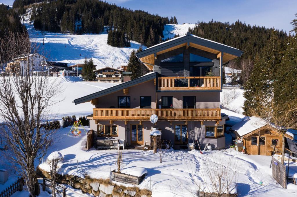 uma casa na neve com uma varanda em Ski in - Ski out Panoramaferienhaus Breitmoos neben Mittelstation em Mittersill