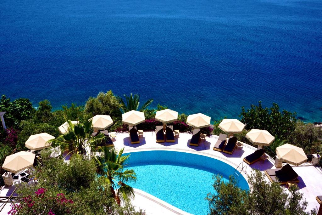 an image of a swimming pool with umbrellas and the ocean at Villa Hotel Tamara in Kaş