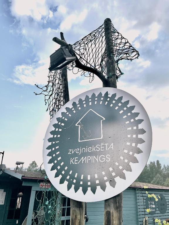 a sign on a pole in front of a building at Camping Zvejnieksēta in Pāvilosta
