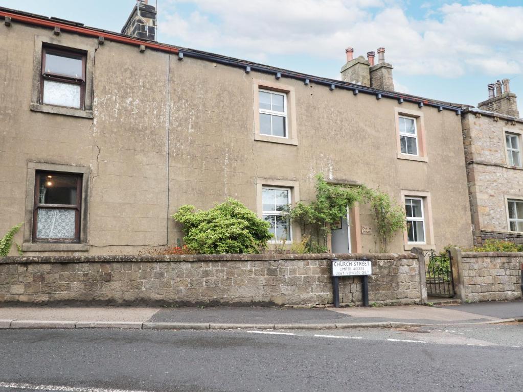 een oud bakstenen gebouw met een bord ervoor bij Dyson House in Skipton