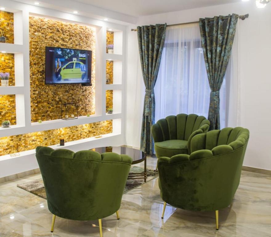 a room with two green chairs and a tv on a wall at Pensiunea Cataleya in Orăştioara de Sus