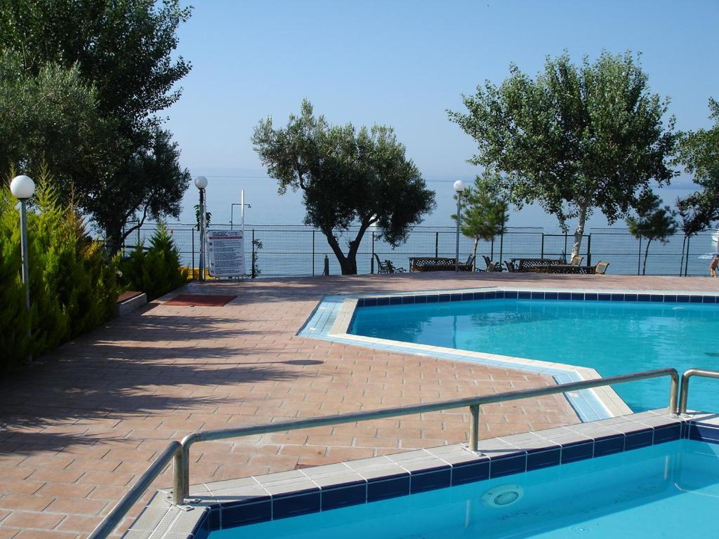 a swimming pool on a brick walkway next to the water at Bungalows Camping Kouyoni in Gerakini