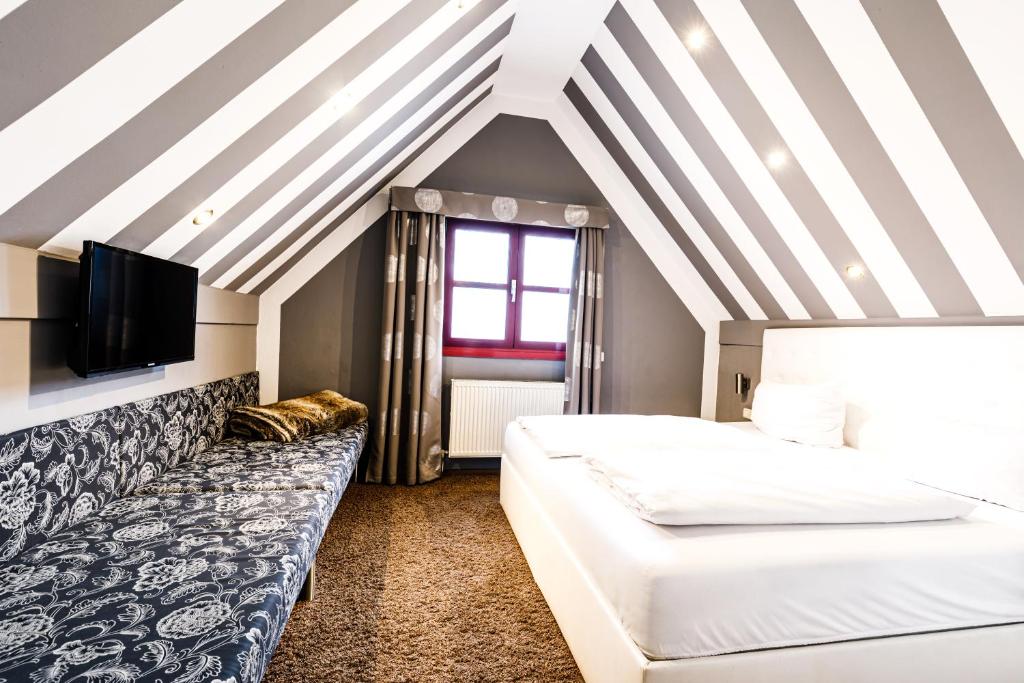 a hotel room with two beds and a couch at Arthotel Restaurant Pfeffermühle in Ingolstadt