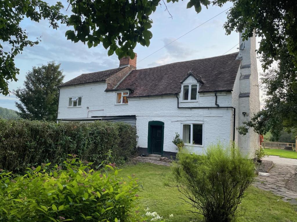 an old white house with a green door at 1 & 2 Foundry Cottages in Sutton Maddock