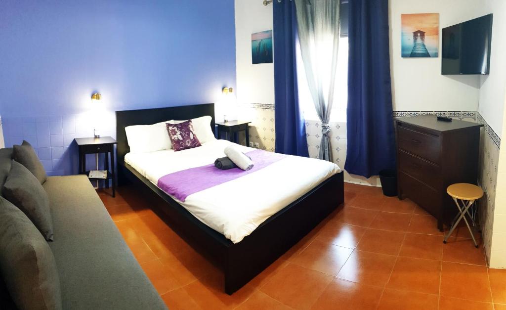 a bedroom with a bed and a dresser and blue curtains at Guesthouse of Alcobaça in Alcobaça