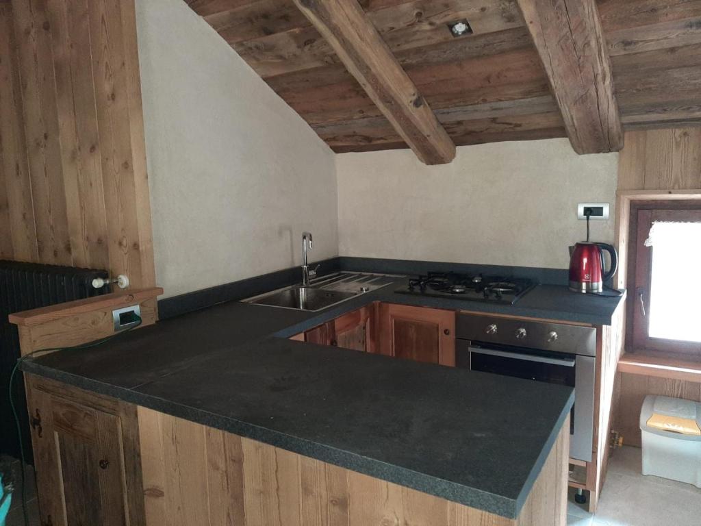 una cucina con piano di lavoro nero e lavandino di grenier barrel a Valgrisenche