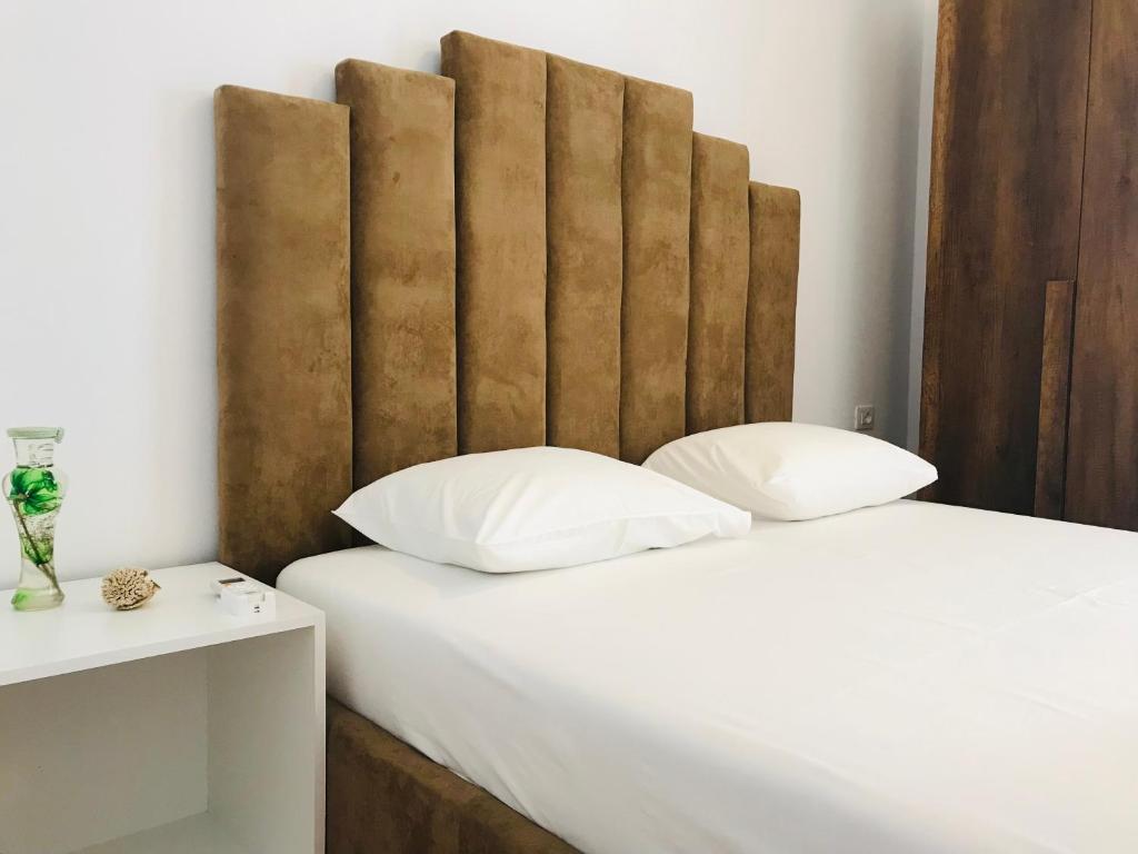 - un lit avec des oreillers blancs et une tête de lit en bois dans l'établissement Enia's Room, à Saranda