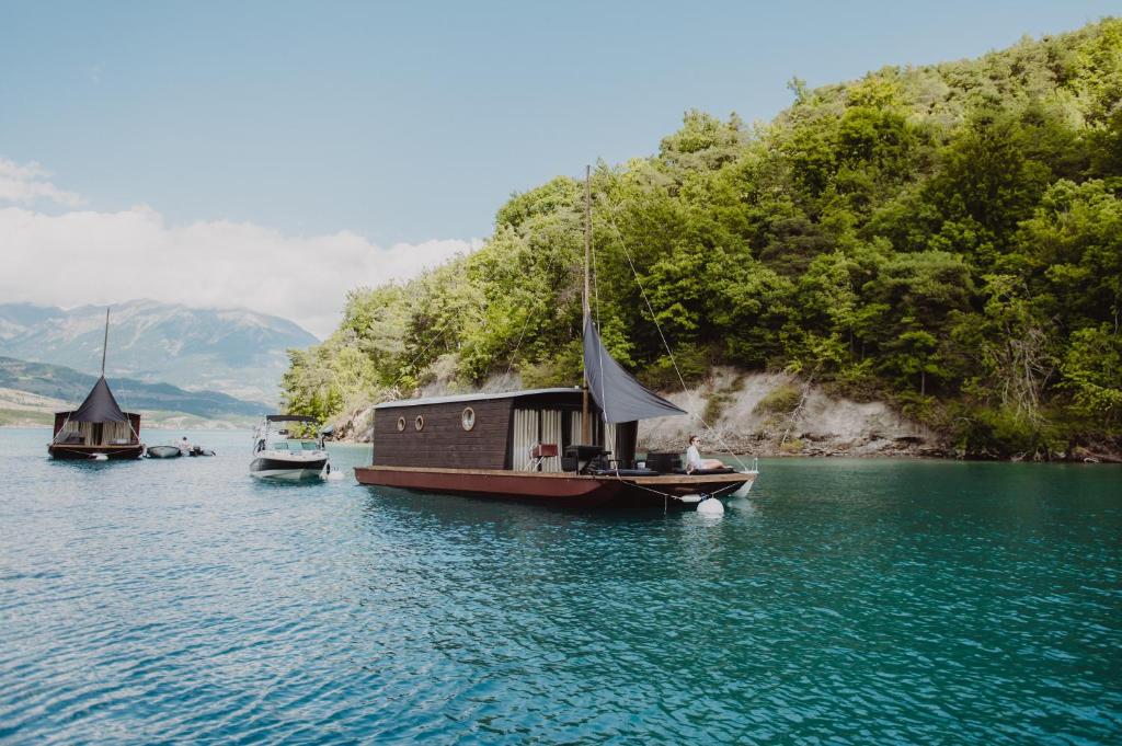 un petit bateau dans l'eau avec d'autres bateaux dans l'établissement Les Toues Cabanées du lac, à Le Sauze-du-Lac