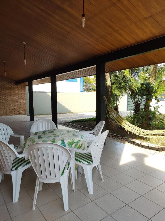 einen weißen Tisch und Stühle auf einer Terrasse in der Unterkunft Casa na Praia do Lázaro em Ubatuba/SP in Ubatuba