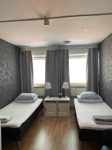 a bedroom with two beds and a desk and two windows at Helsingborgs Vandrarhem, Helsingborg Hostel in Helsingborg