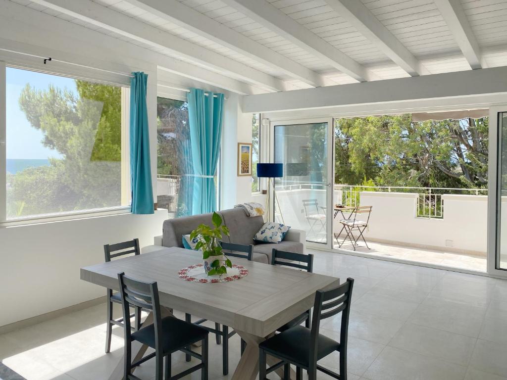 une salle à manger avec une table, des chaises et une grande fenêtre dans l'établissement Attico vista mare in villa antica, à Torre Pali