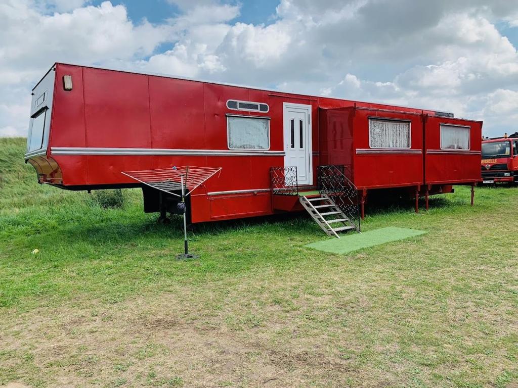 um reboque vermelho está estacionado num campo em Vintage, Circus Holiday Home em Mablethorpe