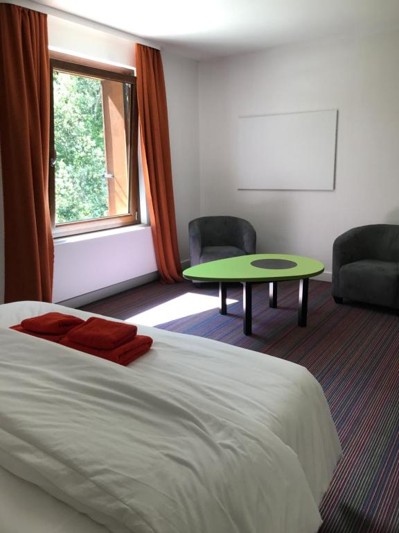 a bedroom with a bed and a table and a window at La maison de Cécile in Ventron