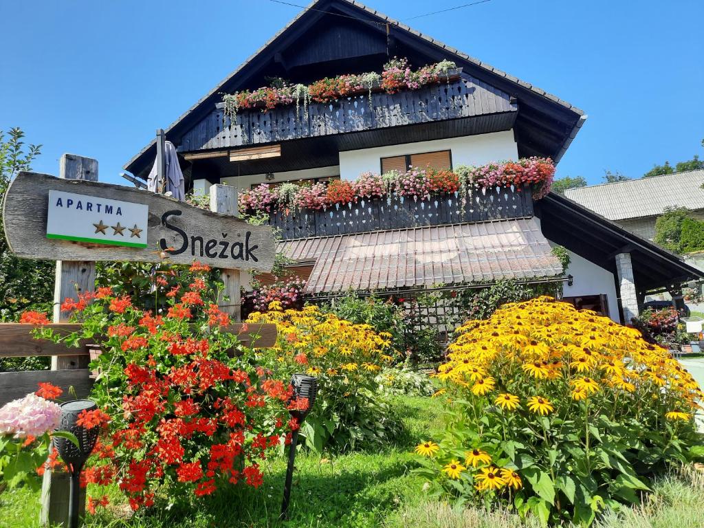 un edificio con muchas flores delante de él en Snežak (Snowman) 2 en Bohinj