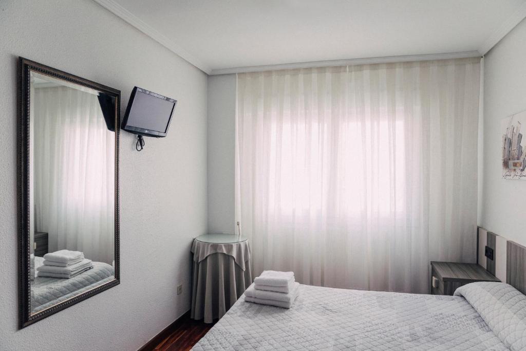 Dormitorio blanco con espejo y cama en Pensión Amaia H VI 00348, en Vitoria-Gasteiz