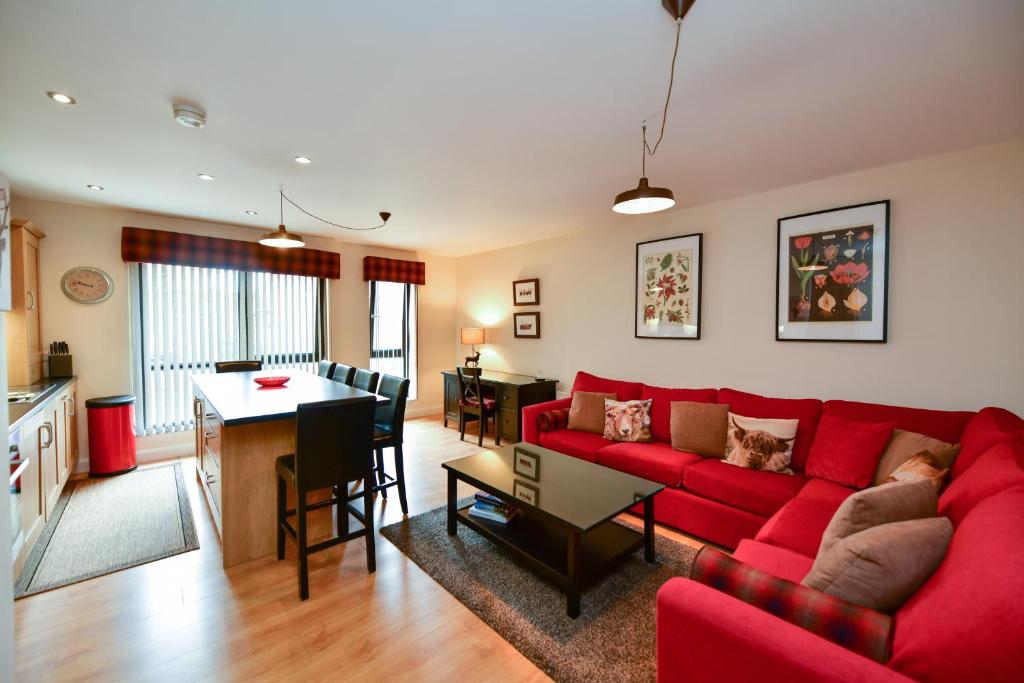 sala de estar con sofá rojo y mesa en West Portland View Apartment A, en Troon