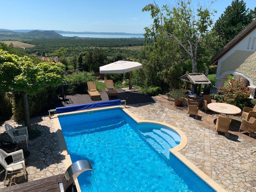 a swimming pool with chairs and a table next to a house at Panorama Pool Residence in Balatonfüred