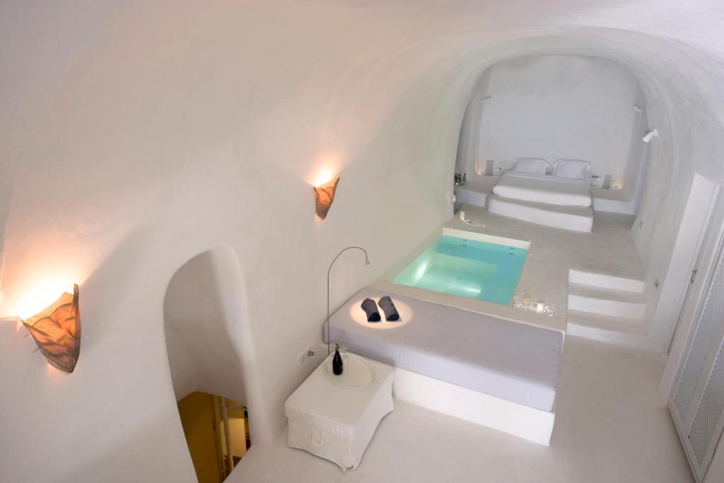 een witte badkamer met een wastafel en een bad bij Lydia Cavehouse in Oia
