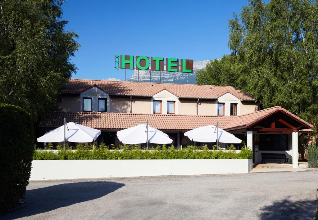 un hôtel avec des parasols en face d'un bâtiment dans l'établissement Logis Des Trois Massifs, à Claix