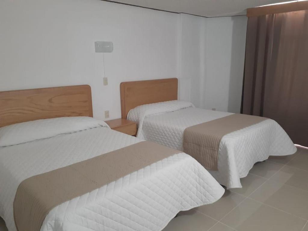 2 camas en una habitación de hotel con sábanas blancas en Leo Hotel, en Jerez de García Salinas
