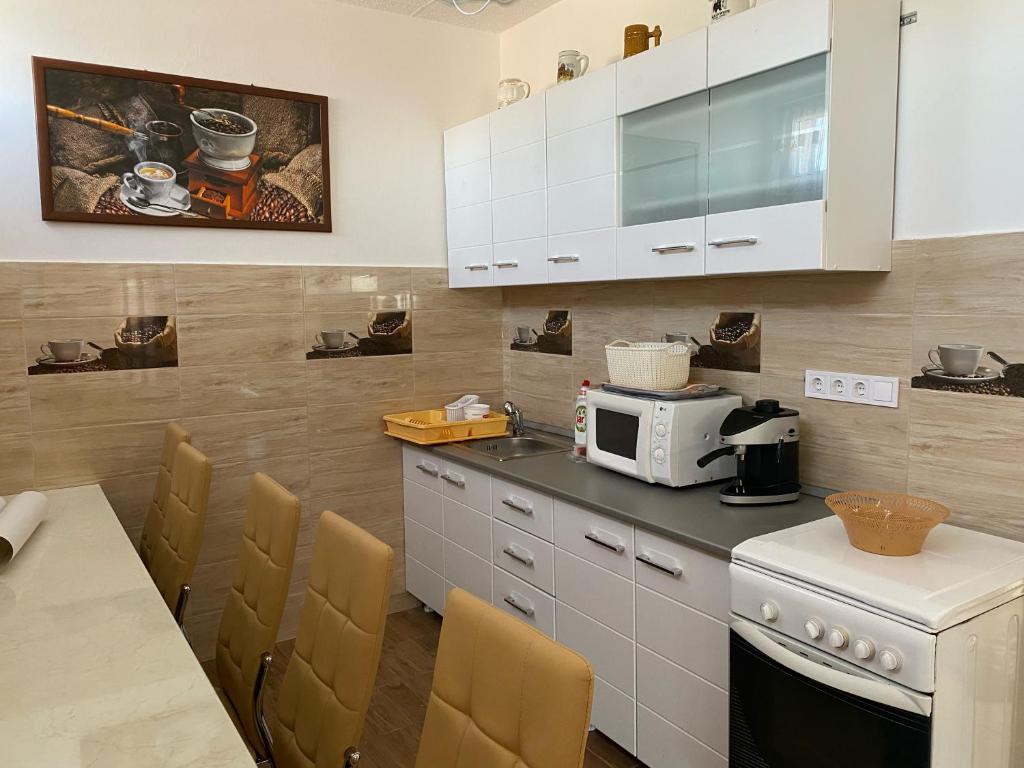 La cuisine est équipée de placards blancs et d'un four micro-ondes blanc. dans l'établissement Erdei vendégház, à Hajdúszoboszló