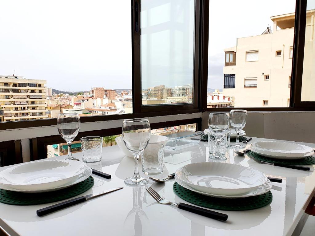 una mesa blanca con platos y gafas y vistas en Fuengirola Towers, en Fuengirola