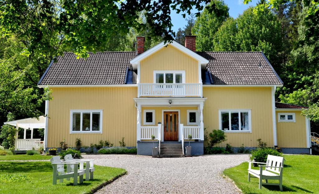 a large yellow house with a white porch at Eden's Garden Cottages in Svanå