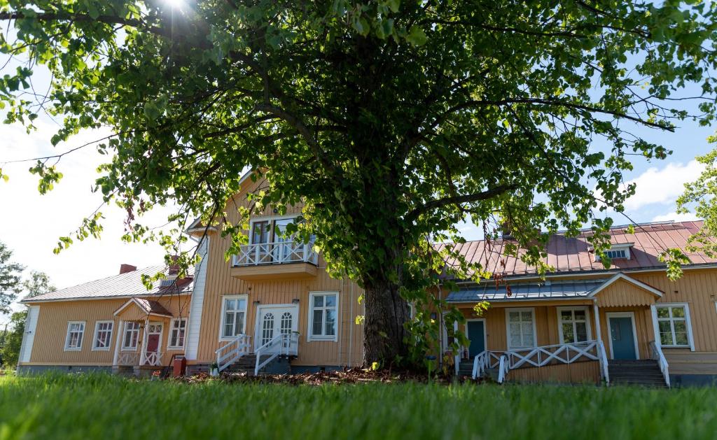 una casa con un albero di fronte di Maaseutuhotelli Juopperin Kartano a Itäkoski