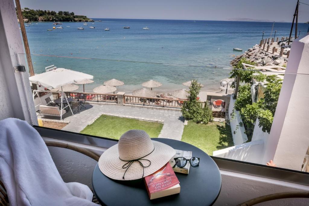 een hoed op een tafel met uitzicht op de oceaan bij Laia Seafront Luxury Apartments in Agia Pelagia