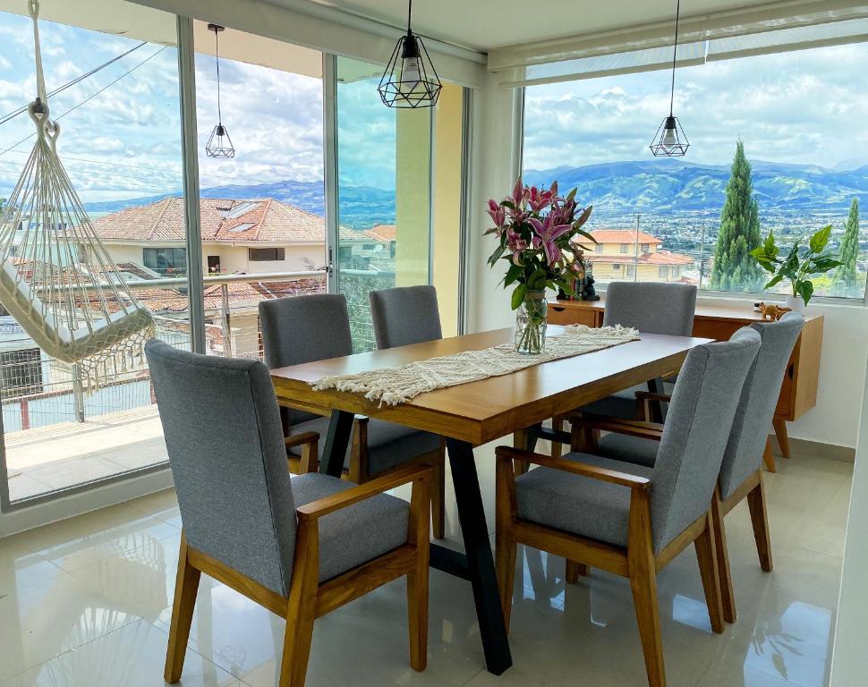 une salle à manger avec une table, des chaises et une grande fenêtre dans l'établissement HERMOSO DEPARTAMENTO CON INCREIBLES VISTAS CUMBAYA, à Quito