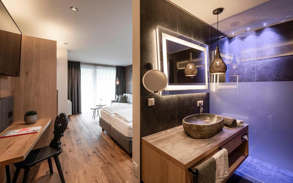 a bathroom with a sink and a bedroom with a bed at Hotel Klostersepp - Neu in Chiusa