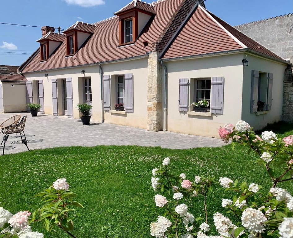 ein Haus mit einem grünen Garten mit Blumen in der Unterkunft Les hauts de campagne in La neuville roy