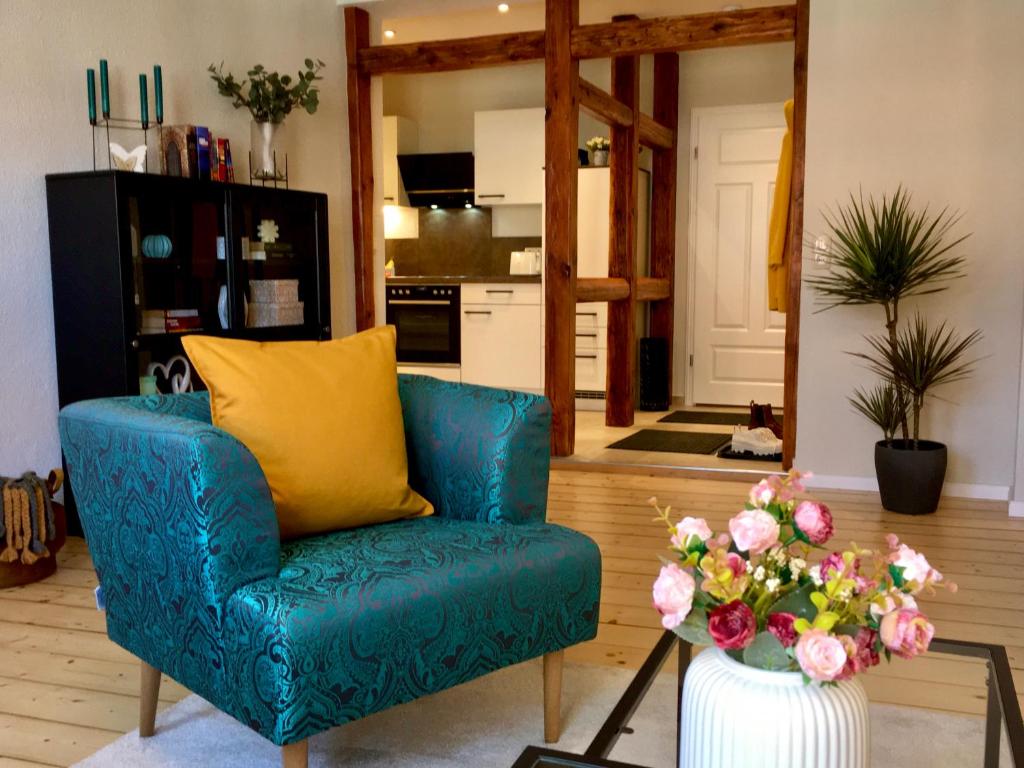 a blue chair in a living room with a vase of flowers at Schöne Ferienwohnung am Mathildenbrunnen in Quedlinburg