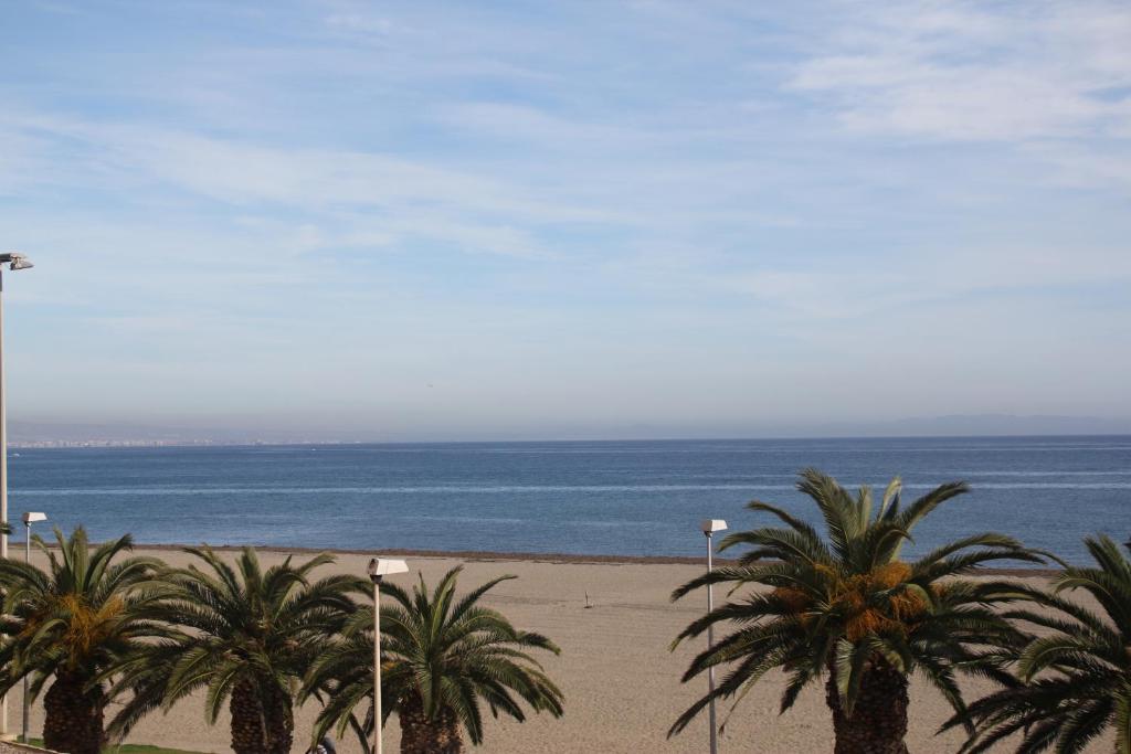 - une plage avec des palmiers et l'océan dans l'établissement Apartamento en primera línea de playa, con vistas a la playa y con wifi, à Roquetas de Mar