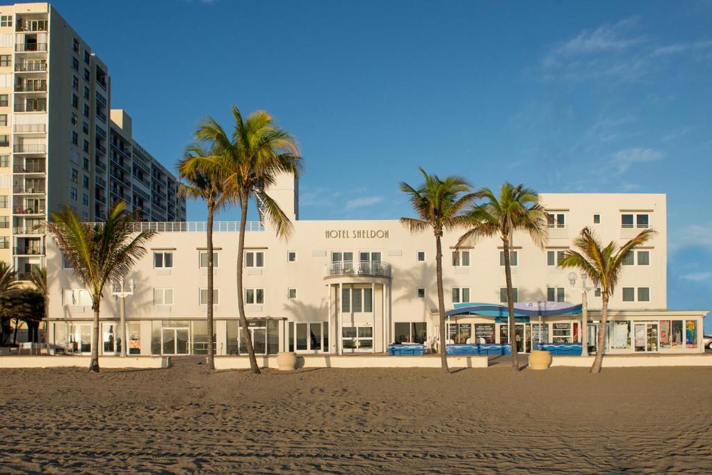 um edifício na praia com palmeiras em frente em Hotel Sheldon em Hollywood