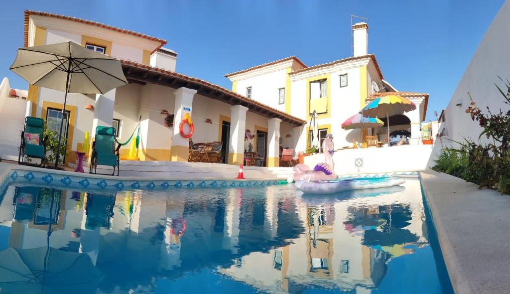 a pool in front of a house with an umbrella at Paradise-AL in Porto Covo