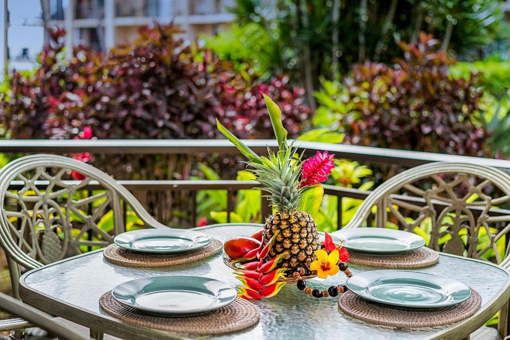 a table with plates and a pineapple on it at Kona Makai 2-102 in Kailua-Kona