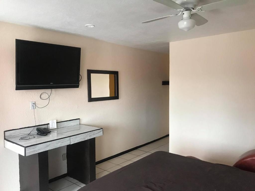 Zimmer mit einem TV an der Wand und einem Schreibtisch. in der Unterkunft COSTA MAR in Ensenada
