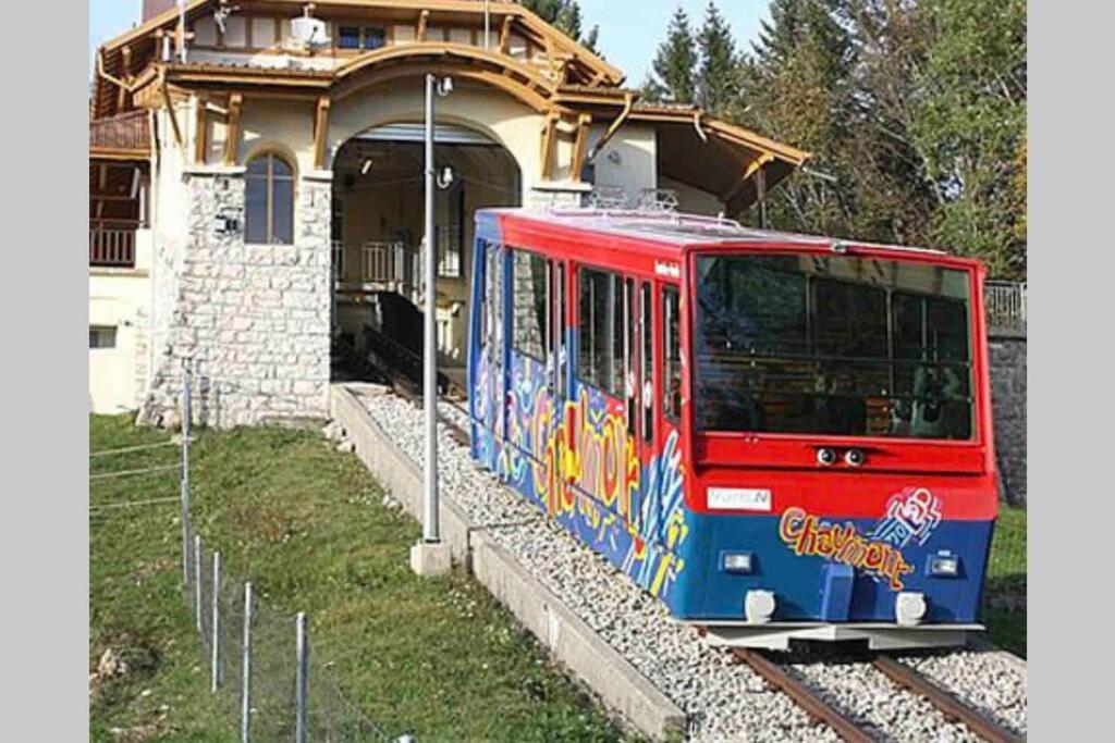 a red and blue train on the tracks in front of a house at Beautiful Cocoon in Neuchâtel
