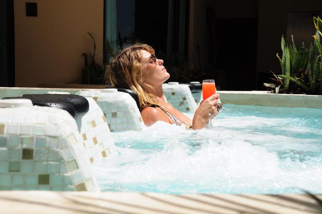 a woman sitting in a swimming pool holding a drink at El Taj Oceanfront and Beachside Condo Hotel in Playa del Carmen
