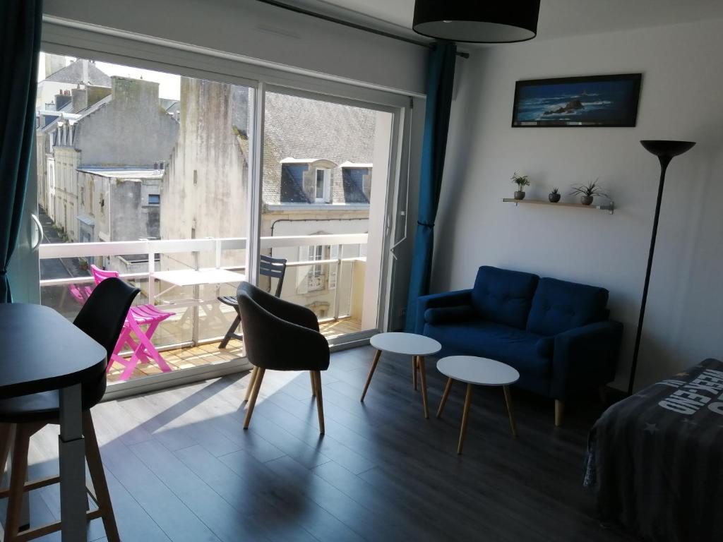 uma sala de estar com um sofá e cadeiras azuis e uma janela em Appartement proche mer et plage em Douarnenez