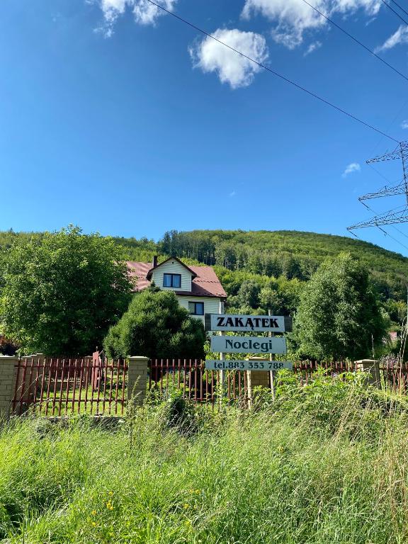 a sign in front of a house with a fence at Zakątek in Porąbka