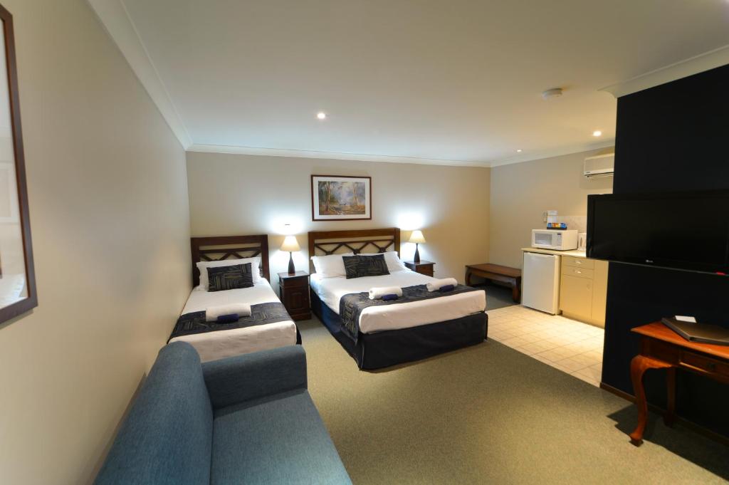 um quarto de hotel com duas camas e um sofá em Wattle Grove Motel em Perth