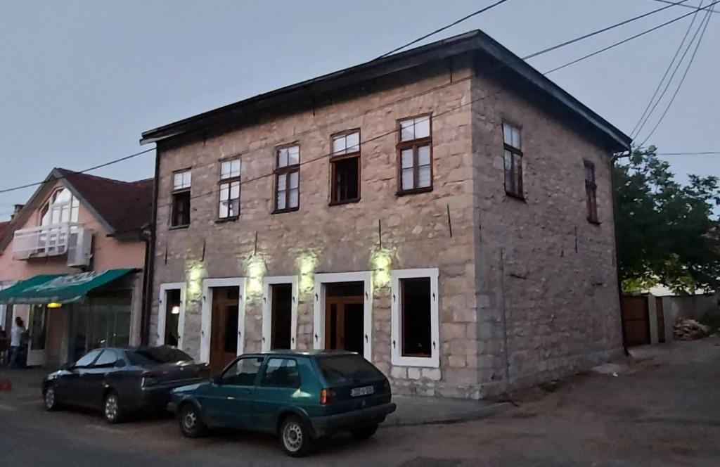 un bâtiment en briques avec deux voitures garées devant lui dans l'établissement Apartmani Aleksandar, à Nevesinje