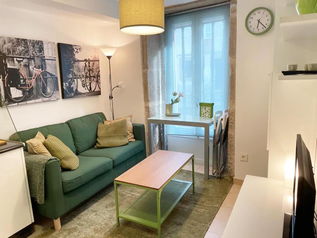 uma sala de estar com um sofá verde e uma mesa em Moss Home em Santiago de Compostela